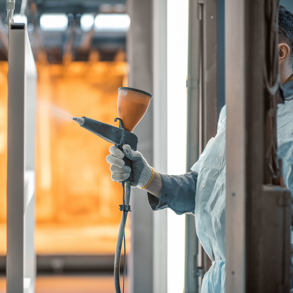 Painter in protective wear paints metal products with powder paint. Powder coating process at the manufacturing. High quality photo
